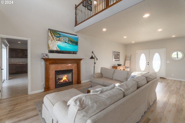 living area featuring light wood-style floors, a high ceiling, baseboards, and a fireplace