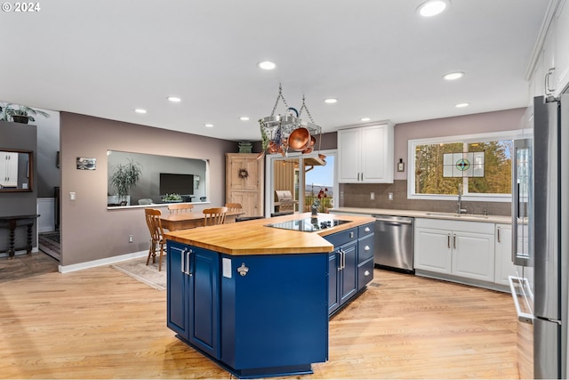 kitchen with white cabinets, wood counters, blue cabinetry, and appliances with stainless steel finishes