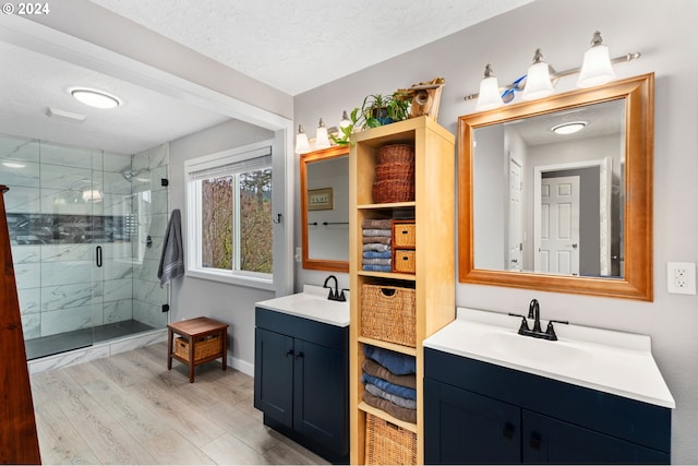 bathroom with hardwood / wood-style floors, vanity, a shower with door, and a textured ceiling