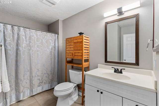 bathroom featuring toilet, vanity, a textured ceiling, and tile patterned floors