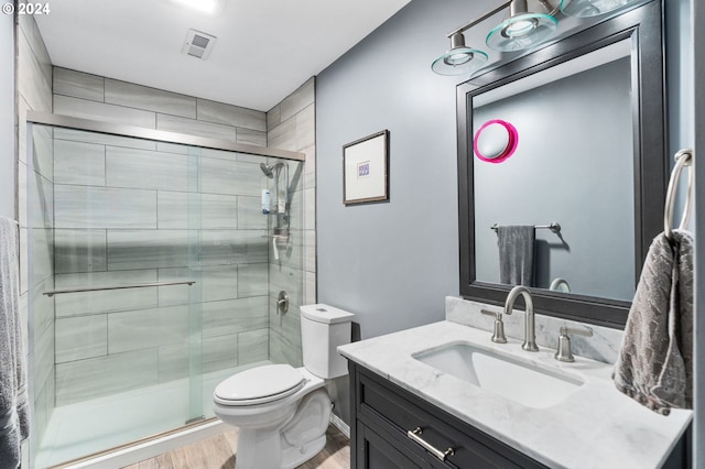 bathroom featuring walk in shower, vanity, wood-type flooring, and toilet