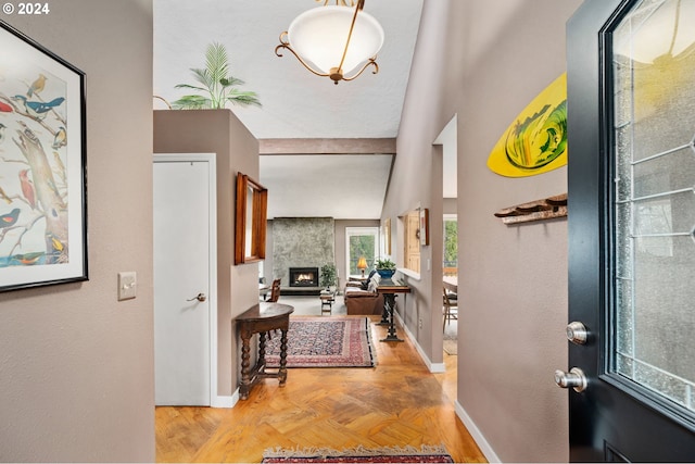 entrance foyer with a large fireplace, light parquet floors, and vaulted ceiling