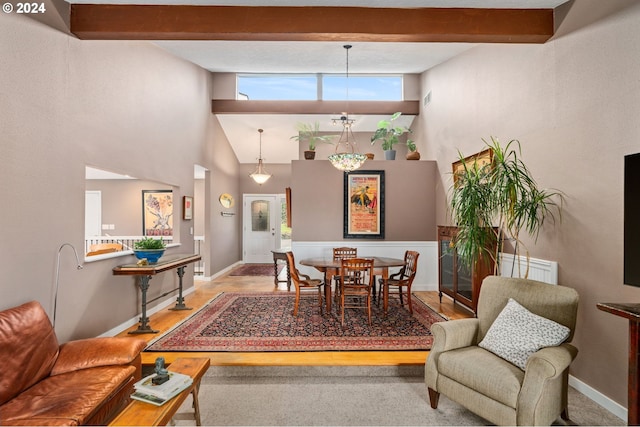 dining space featuring hardwood / wood-style floors, beamed ceiling, and a high ceiling