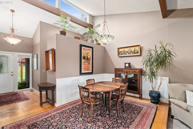 dining space featuring beamed ceiling, high vaulted ceiling, and light hardwood / wood-style floors