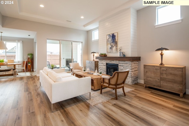 living room featuring wood-type flooring, a fireplace, and a wealth of natural light