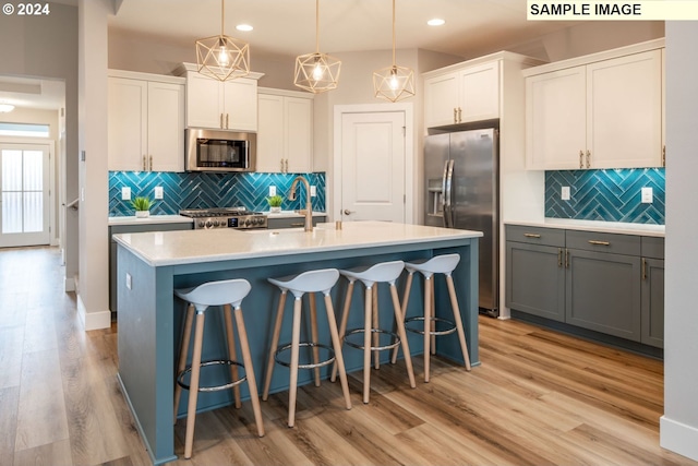 kitchen with gray cabinetry, white cabinetry, appliances with stainless steel finishes, and pendant lighting