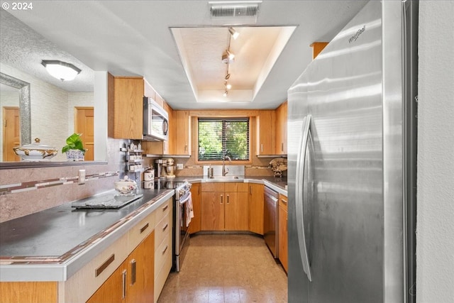 kitchen with appliances with stainless steel finishes, sink, backsplash, a raised ceiling, and a textured ceiling