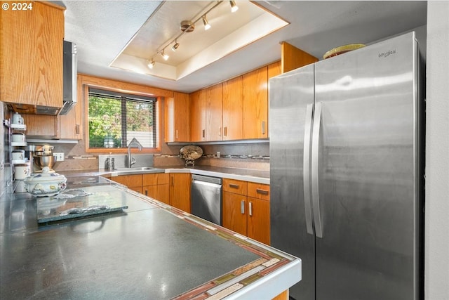 kitchen featuring sink, appliances with stainless steel finishes, a textured ceiling, and a raised ceiling