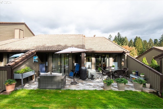 rear view of property with a patio, an outdoor living space, and a lawn