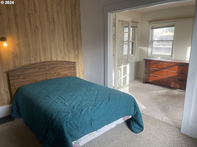 carpeted bedroom featuring wooden walls