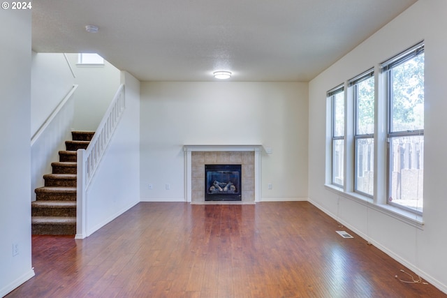 unfurnished living room featuring dark hardwood / wood-style floors and a tiled fireplace