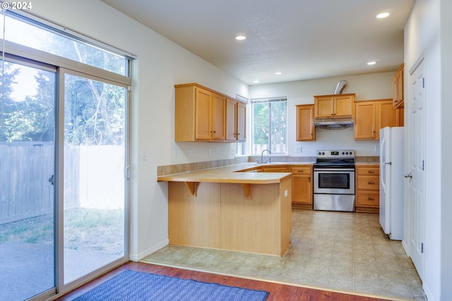 kitchen with sink, stainless steel electric range, a kitchen breakfast bar, kitchen peninsula, and white fridge