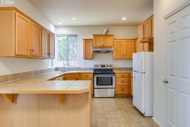 kitchen featuring electric stove, sink, tile counters, kitchen peninsula, and white fridge