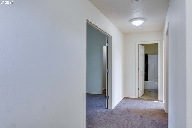 corridor featuring light carpet and a textured ceiling