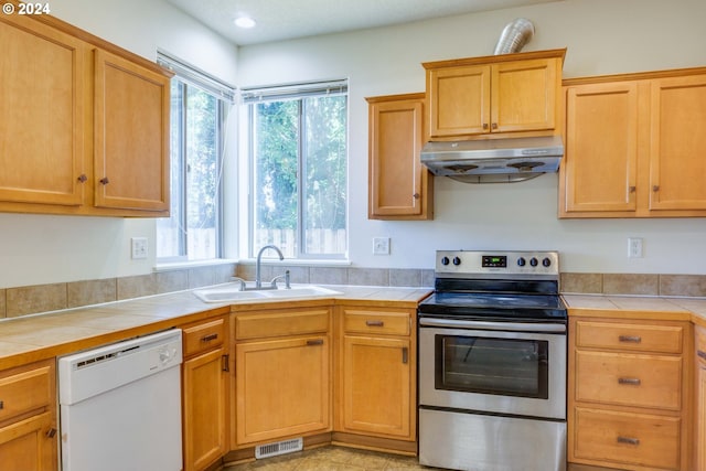 kitchen featuring dishwasher, sink, tile countertops, and stainless steel range with electric stovetop