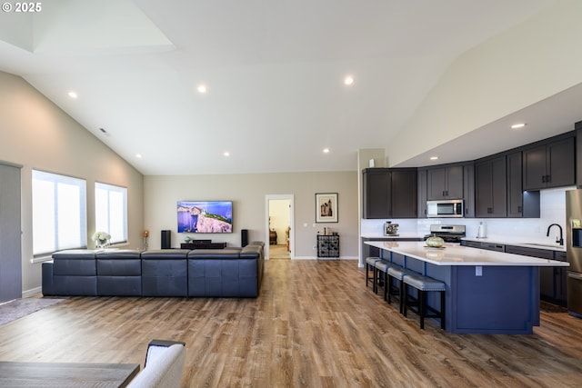 kitchen featuring a breakfast bar, stainless steel appliances, light countertops, open floor plan, and a center island