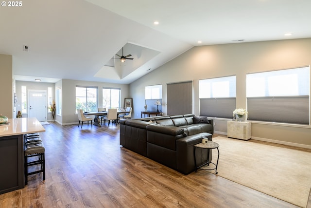 living room featuring a ceiling fan, vaulted ceiling, wood finished floors, and baseboards