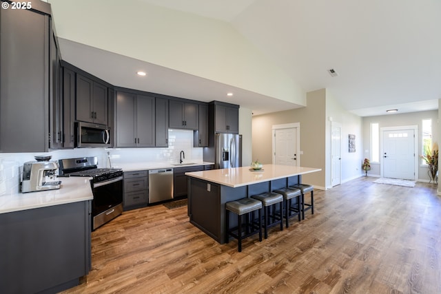 kitchen with a center island, a kitchen bar, light wood-style flooring, stainless steel appliances, and a sink