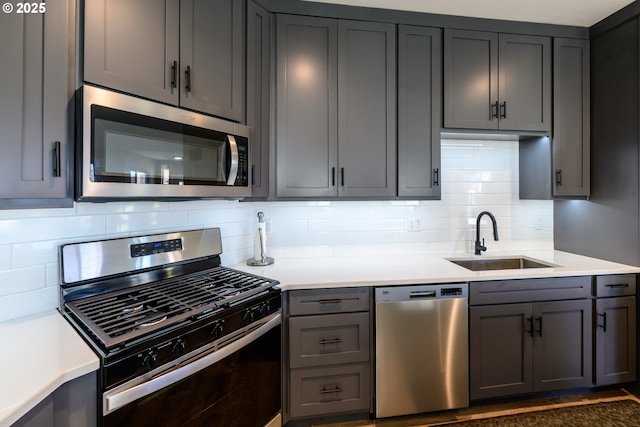 kitchen featuring a sink, light countertops, gray cabinetry, and stainless steel appliances