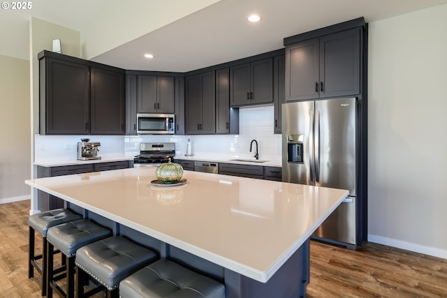 kitchen featuring backsplash, a kitchen breakfast bar, stainless steel appliances, and a sink