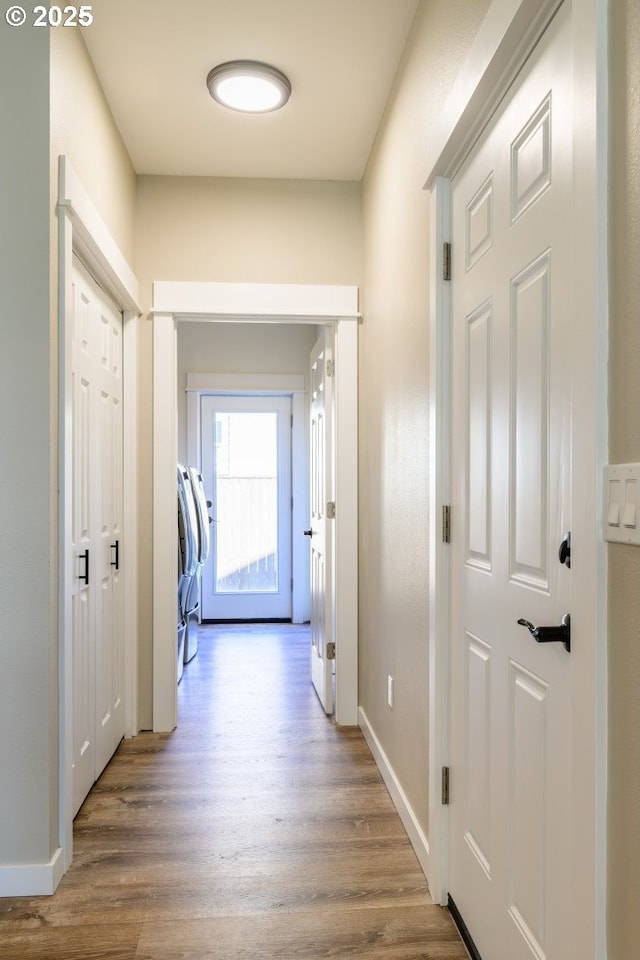 hall with washer and dryer, wood finished floors, and baseboards