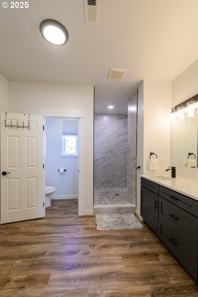 full bath with visible vents, toilet, wood finished floors, walk in shower, and vanity