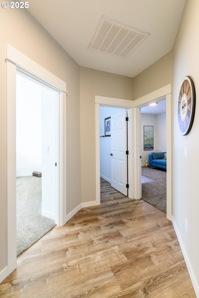 corridor featuring wood finished floors, visible vents, and baseboards