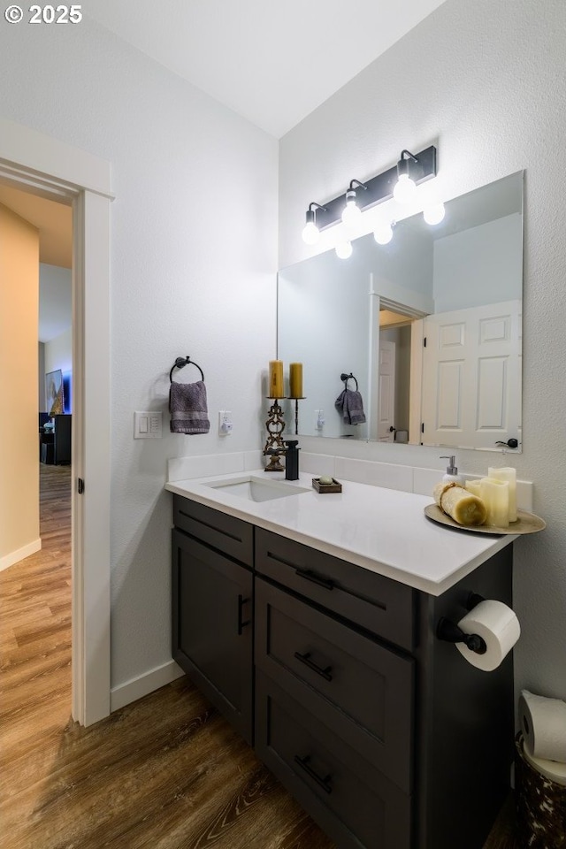 bathroom with baseboards, wood finished floors, and vanity