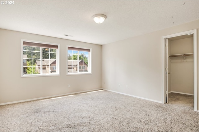 unfurnished bedroom with a walk in closet, carpet, and a closet