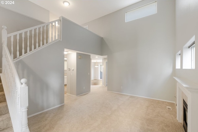 unfurnished living room featuring a high ceiling and light colored carpet