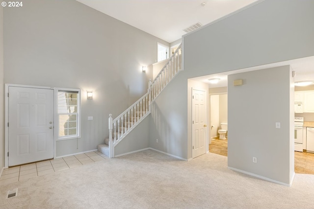 carpeted foyer entrance featuring high vaulted ceiling and plenty of natural light