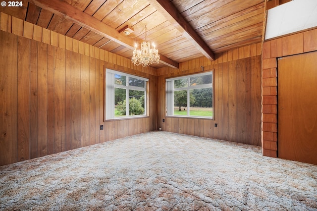 empty room featuring beam ceiling, wood walls, wooden ceiling, and carpet