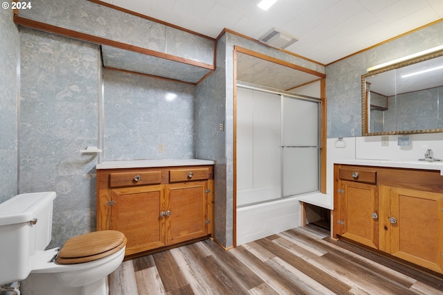 full bathroom featuring vanity, wood-type flooring, bath / shower combo with glass door, crown molding, and toilet