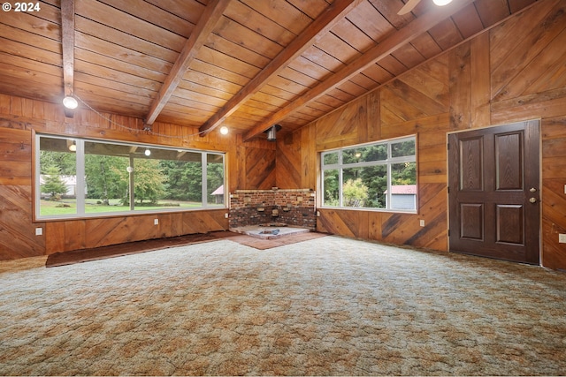 unfurnished living room with wood walls, wood ceiling, carpet flooring, and lofted ceiling with beams