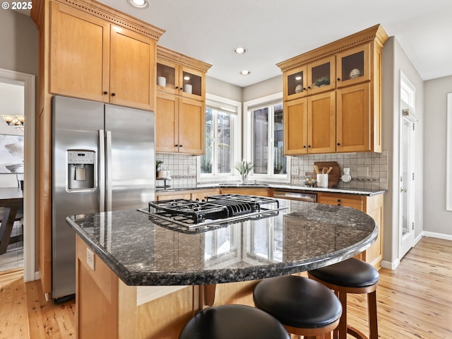 kitchen featuring a kitchen breakfast bar, appliances with stainless steel finishes, a center island, and dark stone counters