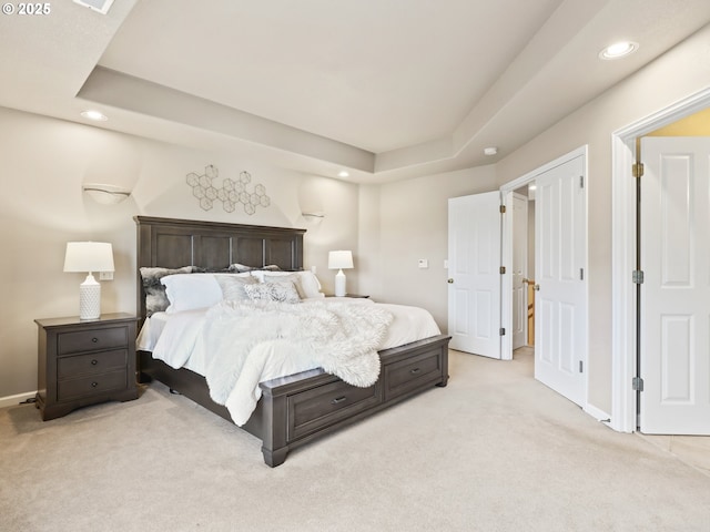 bedroom with light carpet and a raised ceiling