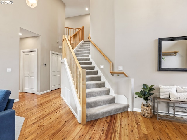 stairway featuring a towering ceiling and wood-type flooring