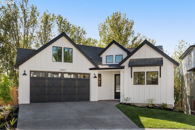 modern inspired farmhouse with concrete driveway, a shingled roof, board and batten siding, and a front lawn