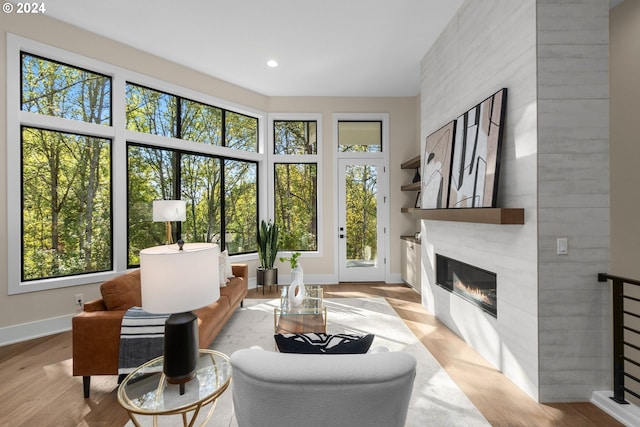 living area featuring a tiled fireplace, a wealth of natural light, and light wood-type flooring