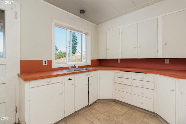 kitchen with white cabinetry, sink, and light tile patterned floors