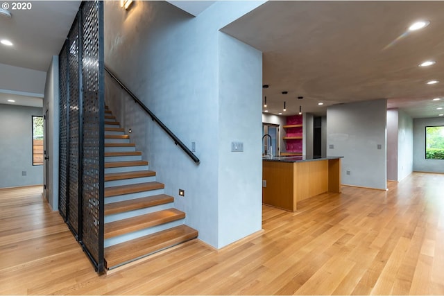 staircase with wood-type flooring, a wealth of natural light, and sink