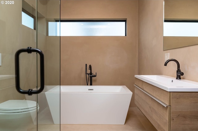 bathroom with tile patterned floors, a wealth of natural light, vanity, and toilet