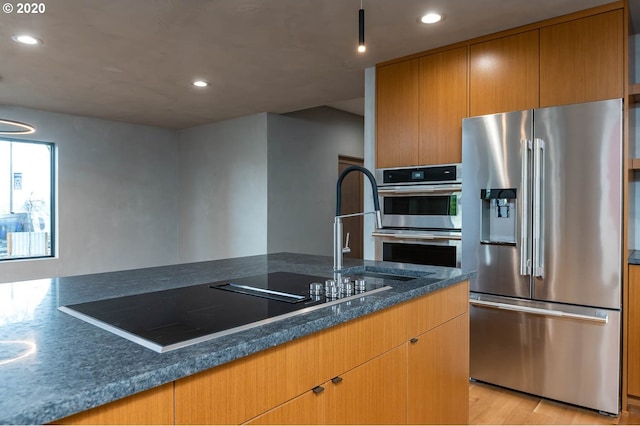 kitchen featuring dark stone countertops, light hardwood / wood-style flooring, and appliances with stainless steel finishes