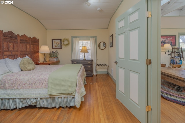 bedroom featuring light hardwood / wood-style flooring, vaulted ceiling, and multiple windows