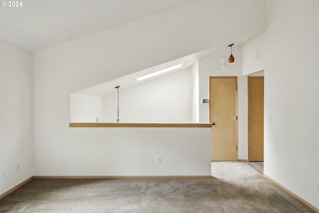 spare room featuring carpet, a skylight, and high vaulted ceiling