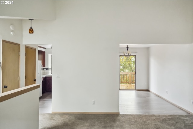 unfurnished room featuring a notable chandelier, light hardwood / wood-style floors, and a towering ceiling