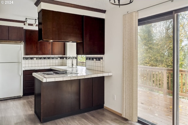 kitchen with tile countertops, decorative backsplash, white fridge, and light hardwood / wood-style floors