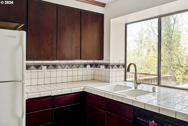 kitchen with tile counters, white refrigerator, sink, and dishwashing machine