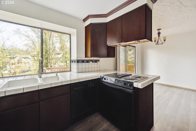 kitchen featuring dark brown cabinetry, sink, tile countertops, a textured ceiling, and black appliances