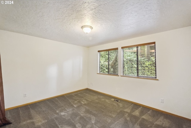 empty room with a textured ceiling and dark colored carpet